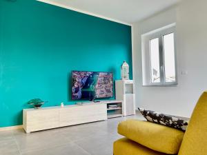 圣莫里吉奥卡瓦纳斯Villa Fiorita的一间客厅,客厅的蓝色墙壁上配有电视