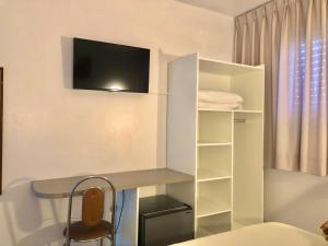 法罗皮利亚Hotel Concatto的客房设有书桌和墙上的电视