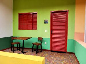 戈亚斯州上帕莱索Atelier & Pousada Chapada的一间红色门的房间,一张桌子和两把椅子