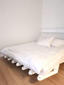 拉诺伊韦维尔Studios des Arcades的白色的床、白色床单和枕头