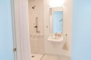 新奥尔良Travelers New Orleans的浴室配有盥洗盆和带镜子的淋浴