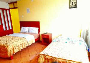 万卡约Hospedaje Las Lilas的酒店客房设有两张床和一张桌子。