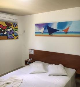 纳塔尔倍加弗洛尔旅馆的卧室内的一张床铺,墙上有绘画作品