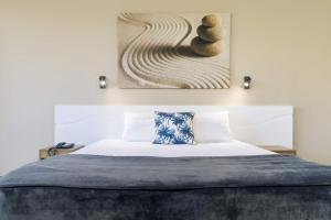 凯恩斯凯恩斯太平洋大酒店的卧室配有一张床,墙上挂有绘画作品