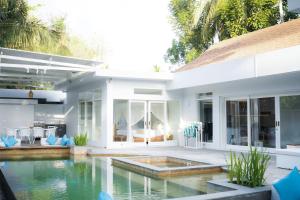 塞隆贝拉纳克Tropik Resort Lombok的一座白色的房子,前面设有一个游泳池
