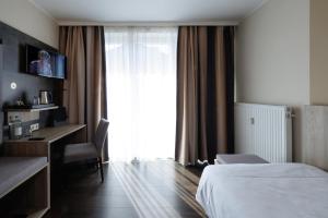 明斯特叶兰特鲁普酒店的配有一张床、一张书桌和一扇窗户的酒店客房