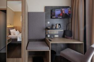 明斯特叶兰特鲁普酒店的小房间设有一张桌子和一台墙上的电视