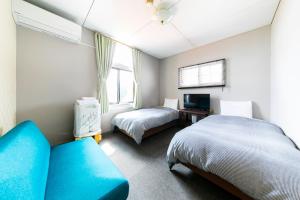北斗市Guesthouse leaf的一间卧室配有两张床和蓝色的沙发