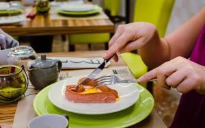 特罗佩阿名利场住宿加早餐旅馆的持叉子、刀子和一盘食物的人