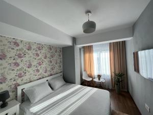 雅西Ballade Apartment的一间卧室配有一张带花卉壁纸的床