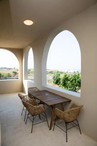 卡马利Olive Villa的用餐室设有2扇拱形窗户和1张木桌及椅子