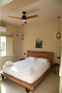 卡马利Olive Villa的一间卧室配有一张带白色床单的床和吊扇。