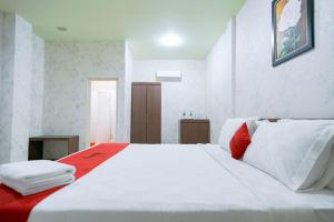 SibolgaRedDoorz Plus @ Jalan FL Lumban Tobing Sibolga的白色的床和红色和白色的枕头