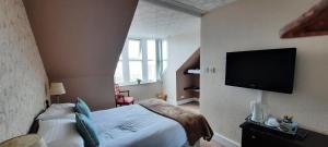 PortknockieVictoria Hotel的一间卧室配有一张床和一台平面电视