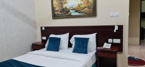 索哈尔Sadaf Hotel Apartments的一张带蓝色枕头的床和一张墙上的照片