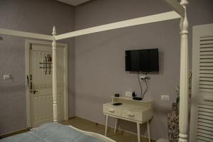 MundraThe Village Resort Mundra的卧室配有一张床,墙上配有电视。