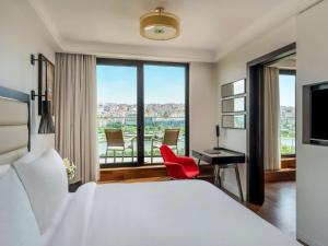 伊斯坦布尔莫凡彼伊斯坦布尔金角酒店的酒店客房配有一张床和一张带红色椅子的书桌