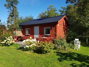 格兰纳Södra Kärr 4的一间红色小屋,在院子里设有桌子和椅子