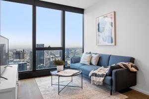 墨尔本CLLIX Australia 108 Apartments的客厅设有蓝色的沙发和大窗户