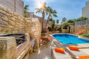萨奈特Djar ta Menzja 2 Holiday Home的后院设有游泳池和石墙