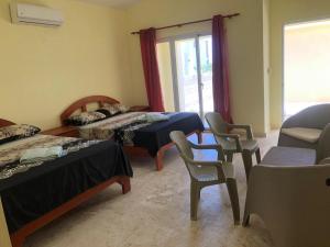 蓬塔露奇亚Punta Rucia Cristal Beach的客房设有两张床、椅子和窗户。