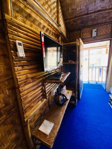 古瓦哈提Tridhara HomeStay的一间设有木墙的客房,配有电视