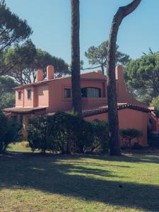 卡斯卡伊斯Onyria Quinta da Marinha Villas的前面有树木的粉红色房子