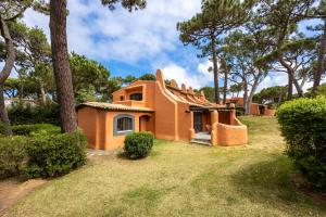 卡斯卡伊斯Onyria Quinta da Marinha Villas的一座小橘子房子,位于一个树木繁茂的院子内