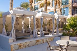拉斯维加斯Staybridge Suites Las Vegas - Stadium District的一个带桌椅和遮阳伞的庭院
