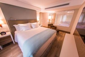 纳塔尔Vogal Luxury Beach Hotel & SPA的一间设有大床和窗户的酒店客房