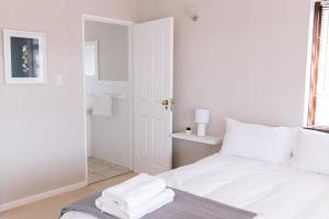 东伦敦Nahoon Beach Villas Self Catering Apartments的白色卧室,配有带毛巾的床