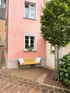 萨尔堡Uriges Ferienhaus in der Altstadt von Saarburg mit Sauna, Kinderspielecke, 1000Mbit Wlan, 1 Minute vom Wasserfall entfernt的坐在粉红色建筑前面的长凳