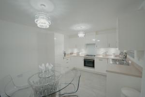 罗瑟勒姆Willow Heights Modern 5-7 Persons/3 Bed Detached的白色的厨房,配有玻璃桌