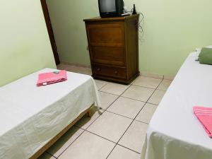 特雷斯拉瓜斯Hotel Solaris的一间设有两张床的房间和一个带梳妆台的电视