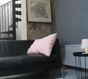豪达Achterhuis Slapen en Eten的黑色皮沙发,上面有粉红色枕头