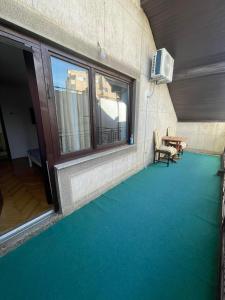 普里什蒂纳Guesthouse 12a的客房铺有绿色地板,设有窗户和桌子。
