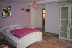 TrézanLe Moulin,19 bis rue de Beaudon, 45330 Augerville la riviere的卧室配有白色床和粉色毯子