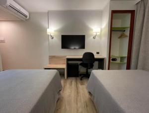 圣地亚哥Diego de Almagro Providencia Express的酒店客房设有两张床、一张桌子和一台电视。