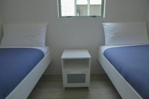 科罗曼德镇奥马鲁湾假日公园的两张位于房间的床,中间有一张小桌子