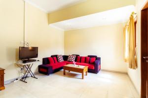 坎古Sakura Guest House的客厅配有红色沙发和电视