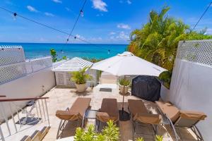 圣詹姆斯Bianca Bay 3 Bedroom West Coast Beach Front Villa的一个带椅子和遮阳伞的庭院和大海