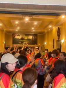 金边奈斯旅馆的一群人站在一个房间里,手放在空中