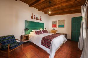 危地马拉安地瓜Barbara's Boutique Hostel的一间卧室配有一张带绿色床头板的床和一把椅子