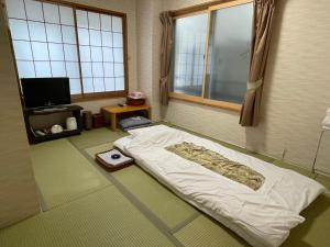 东京三河屋旅馆的一间带床的卧室,位于带窗户的房间内