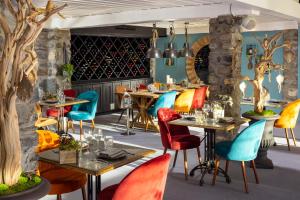 谷雪维尔Hôtel Courcheneige的一间餐厅,房间内设有五颜六色的椅子和桌子