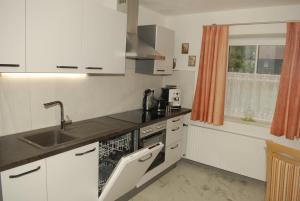 哈尔施塔特Ferienwohnung bon WAB的厨房配有白色橱柜、水槽和窗户。