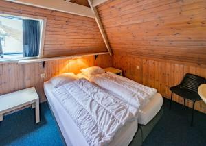 KinnumTerschelling Natuurlijk的木制客房内的一间卧室,配有一张床