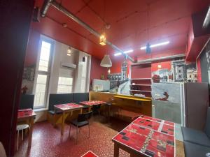 华沙Oliwka Hostel的带2张桌子的餐厅以及带红色墙壁的厨房