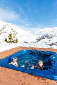 利维尼奥BAITA NOEMI的两名儿童在雪地的热水浴池中游泳