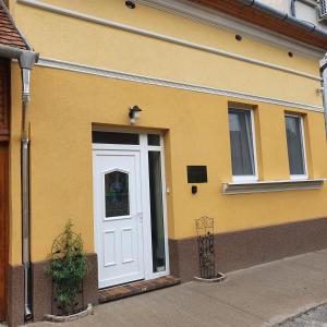 德布勒森Jégmadár Apartman的黄色的建筑,有白色的门和窗户